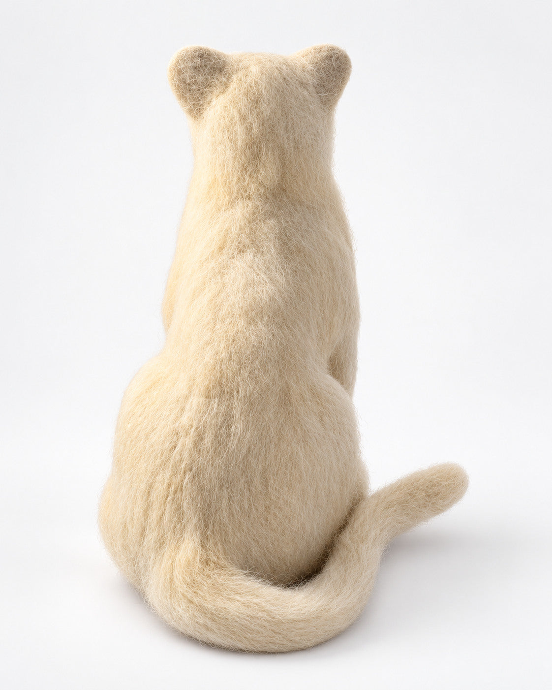 Back view of the felt lion cub figure, showing its ears, soft coat texture and tail
