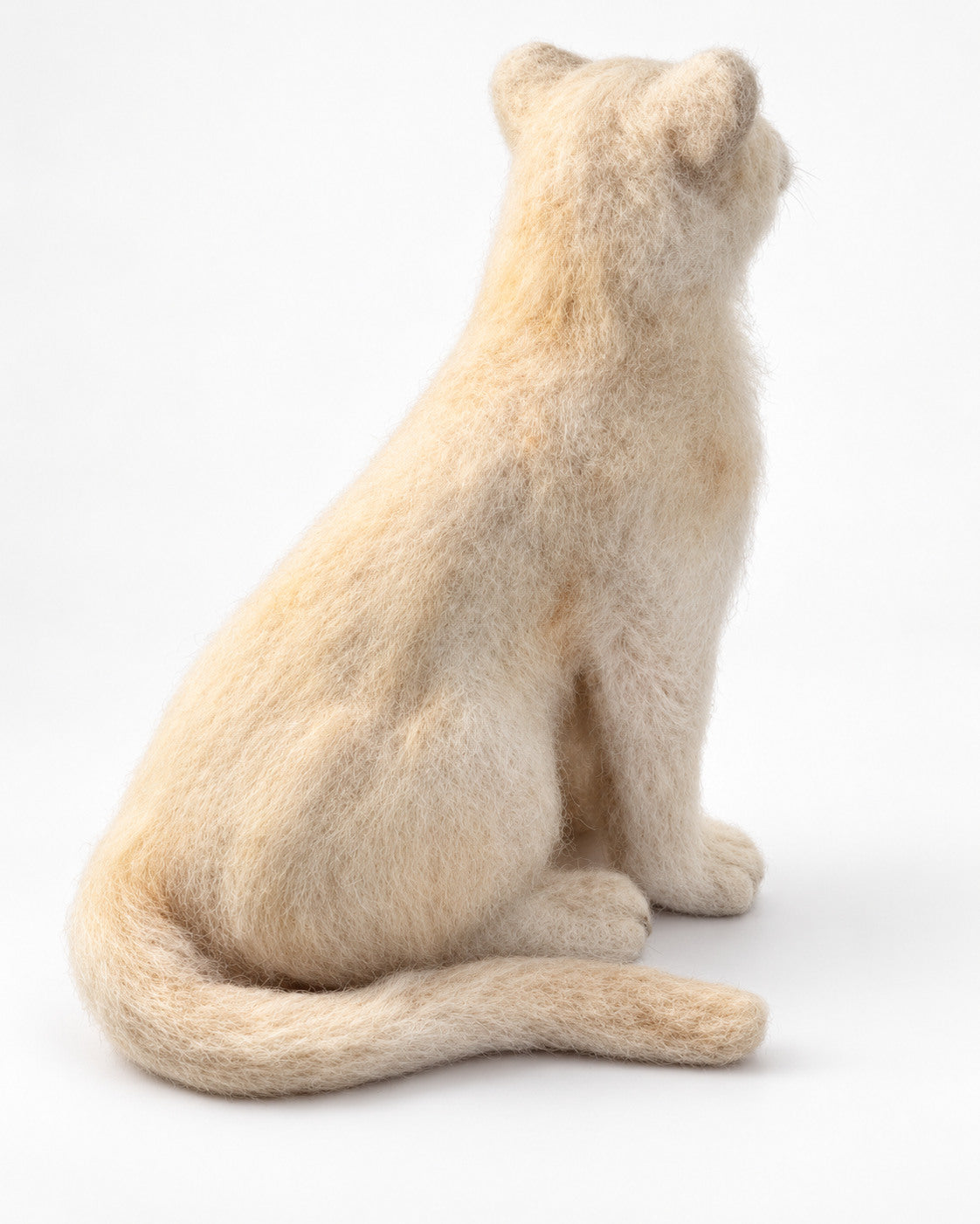 Rear-side view of the cream felt lion cub sculpture with curled tail